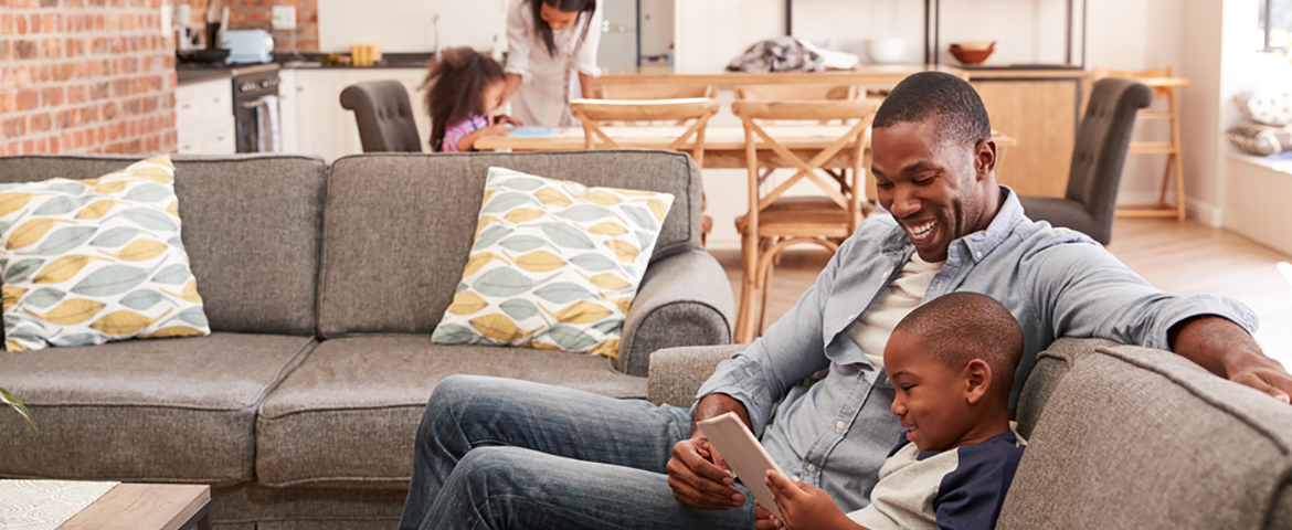 Father and child looking at laptop on couch